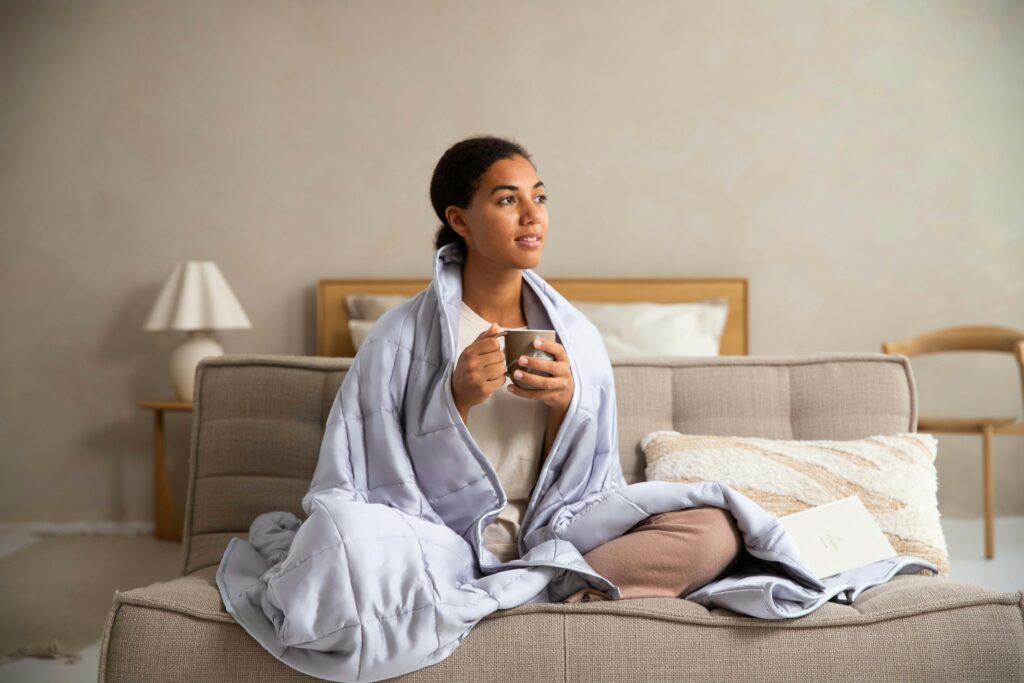 毛布にくるまって温かい飲み物を飲む女性