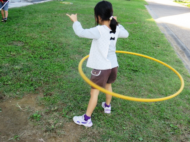 庭でフラフープをしている女の子の後ろ姿
