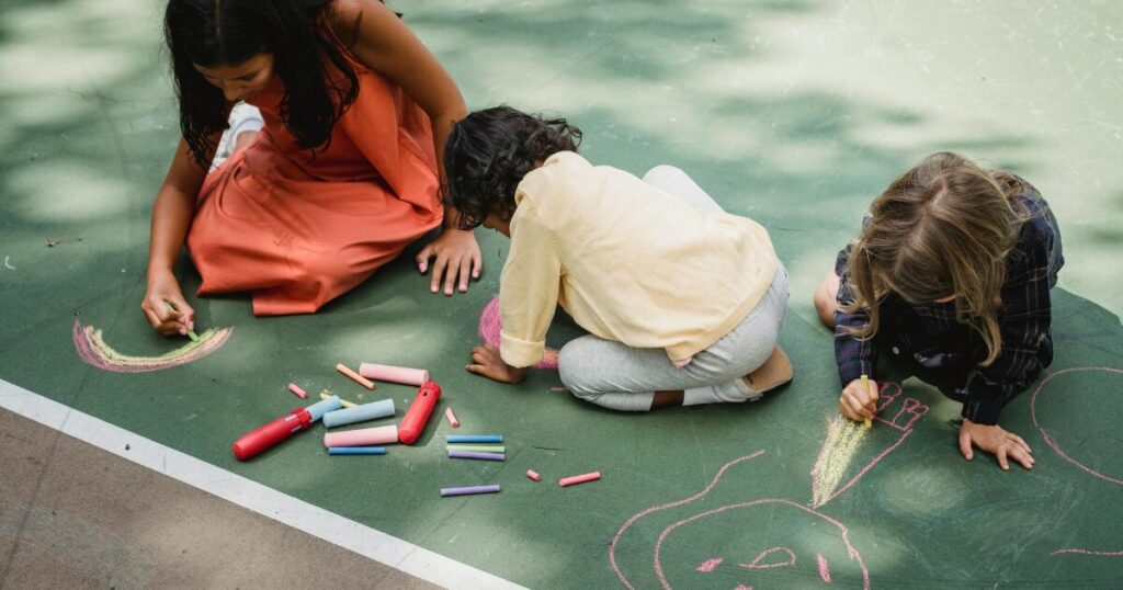 コンクリートの庭でお絵描きする子ども
