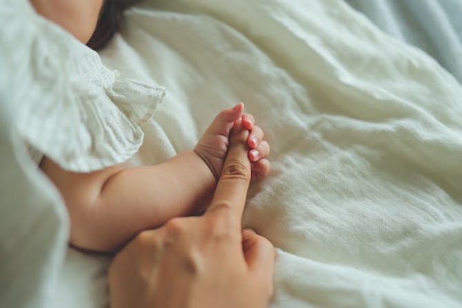 ママの手を握る赤ちゃんの手の写真