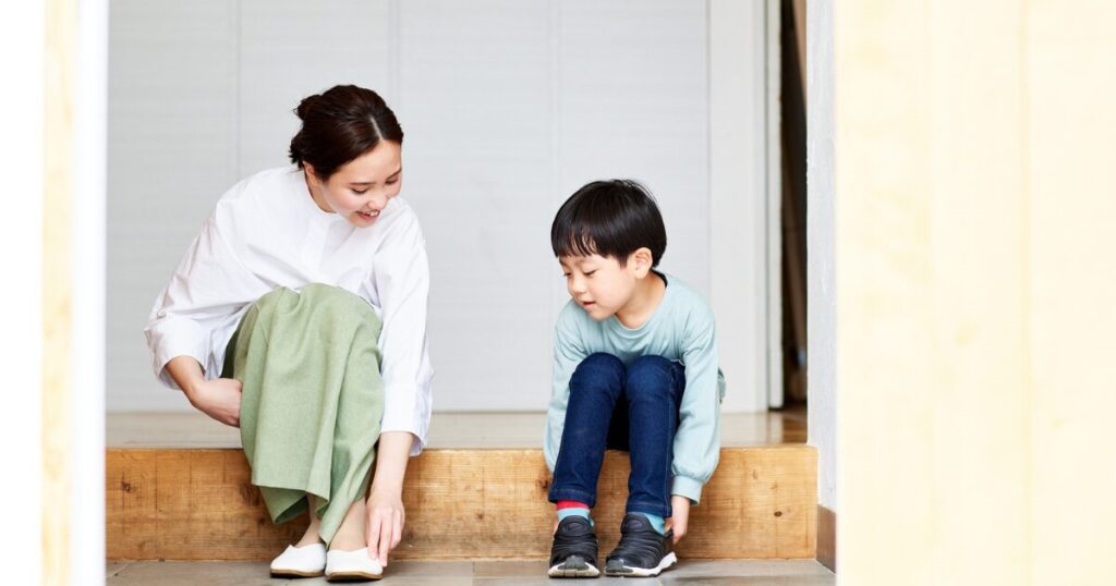 玄関で靴を履く親子